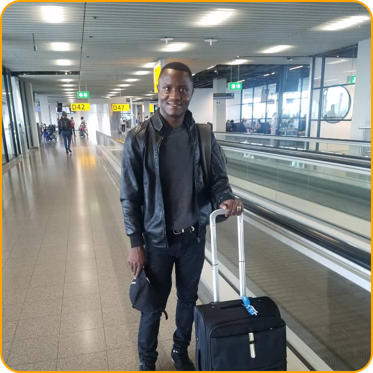 Philbert, a student from Rwanda, is smiling with a suitcase in the airport as he arrives in Ireland to study abroad.